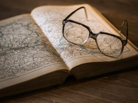 A pair of glasses sitting on an older-looking book open to an image of a map.