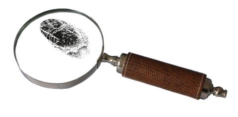 A magnifying glass with a fingerprint in black ink under the glass.