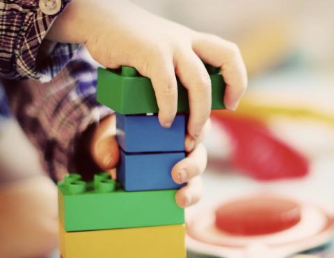 A child's hands holding a stack of Duplo-style bricks