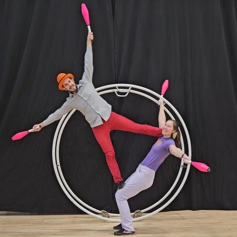 two jugglers holding clubs, doing acrobatics and balancing