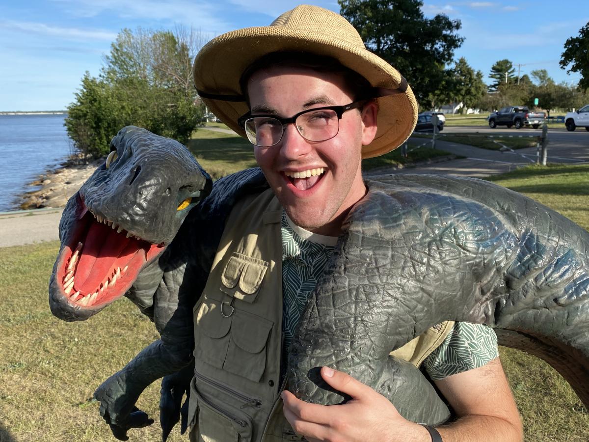 Curt Strutz smiles and holds Velociraptor model